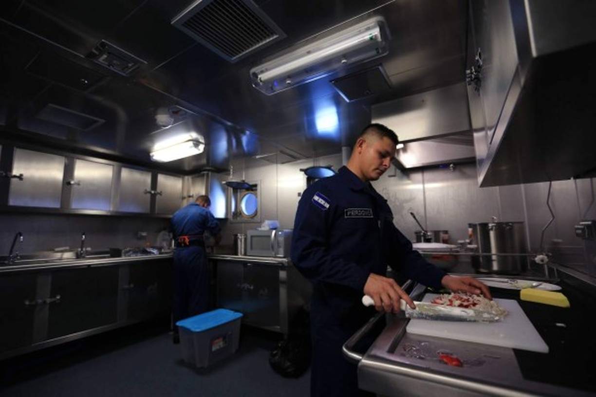 La cocina con una estufa, horno, extractor de humo, licuadora, baño maría y estantes para almacenar utensilios de cocina.