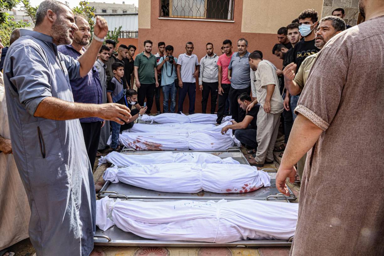 Familiares envuelven los cuerpos de sus seres queridos fallecidos durante un bombardeo.