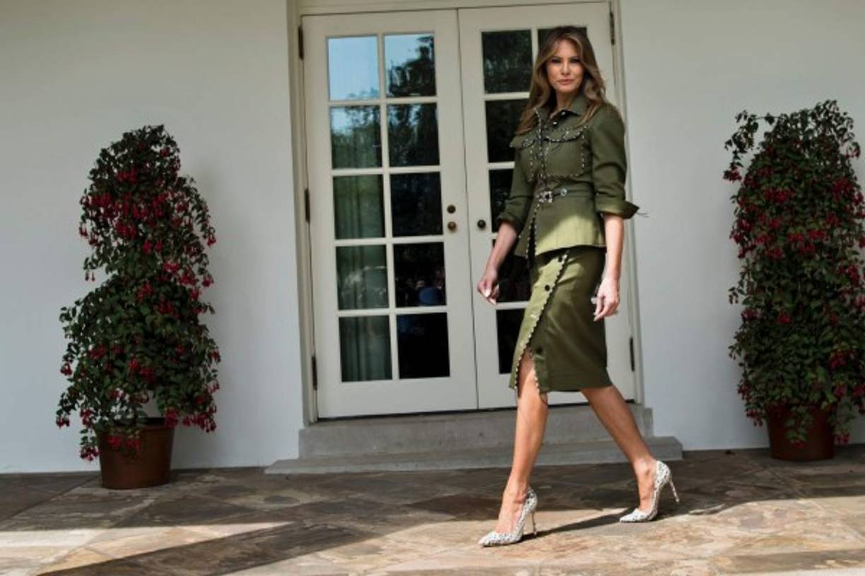 Melania optó por utilizar un traje de dos piezas en verde oliva inspirado en un estilo militar. El look consistió en una chaqueta con botones, bolsillos frontales y corte a la cadera, y una falda por debajo de la rodilla con los mismos botones de la chaqueta y con abertura lateral, de la colección de privamera de Altuzarra, valorado en 4,100 dólares.