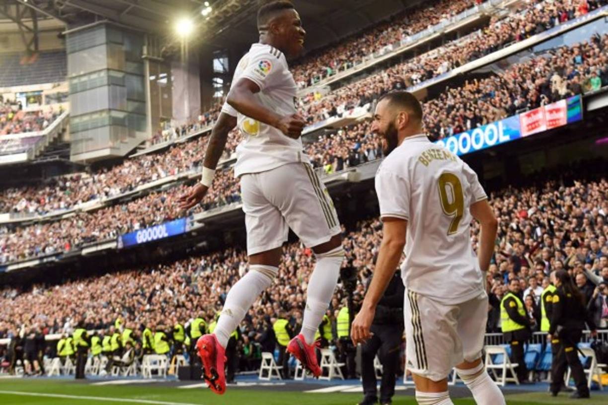 Vinicius salta sobre Benzema para celebrar el gol.