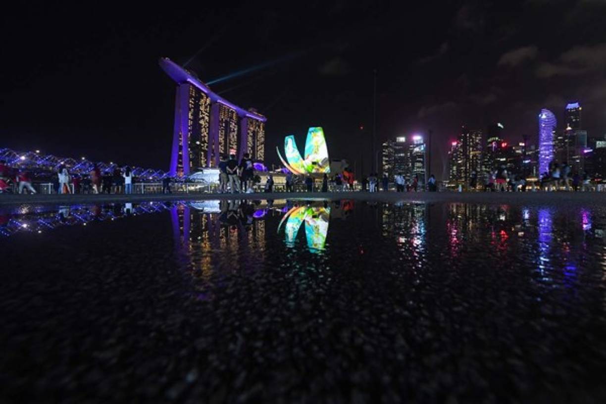 SINGAPUR. La gente observa cómo el área de Marina Bay se ilumina como parte de las celebraciones de Nochevieja en Singapur el 31 de diciembre. 2020. (Photo by Roslan RAHMAN / AFP)