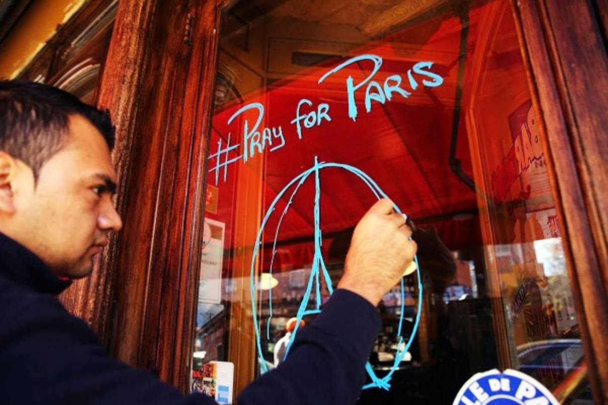 Un joven en Nueva York dibuja en un vidrio el emblema que se ha difundido por redes sociales tras los atentados de París con el hashtag #prayforparis.