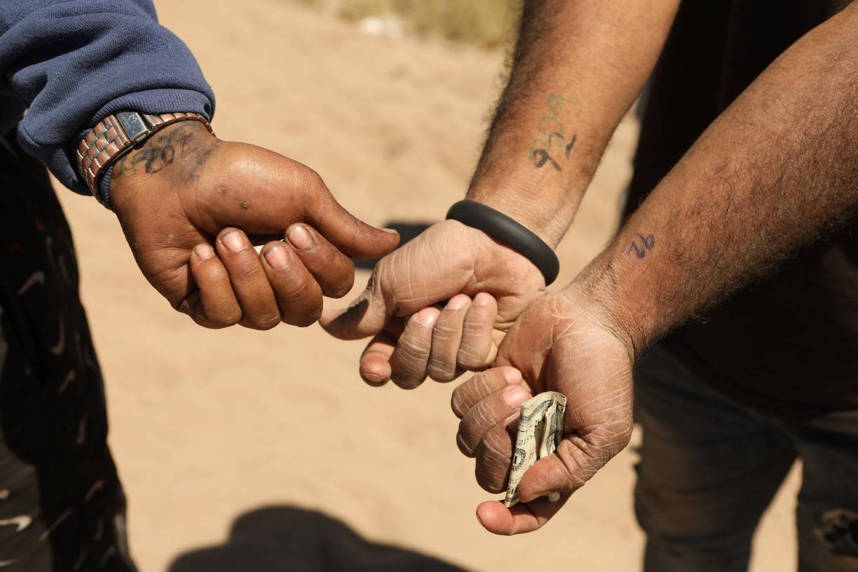 Venezuelan migrants show the numbers marked on their wrists to organize themselves to be processed by the Border Patrol El Paso Sector, Texas, after crossing from Ciudad Juarez, Mexico on May 8, 2023. Mexican President Andres Manuel Lopez Obrador said Monday that he would discuss migration policy with his US counterpart Joe Biden ahead of the lifting of pandemic-era border restrictions this week. The video call on Tuesday would cover "migration, fentanyl and development cooperation," Lopez Obrador told reporters, as the two countries brace for a possible wave of migrants at their shared border. (Photo by HERIKA MARTINEZ / AFP)