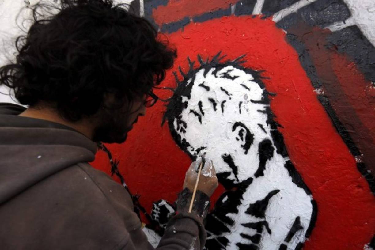 YEMEN. Arte contra la guerra. Un artista yemení pinta un graffiti en protesta por el conflicto y la difícil situación económica en Saná. Foto: EFE/Yahya Arhab