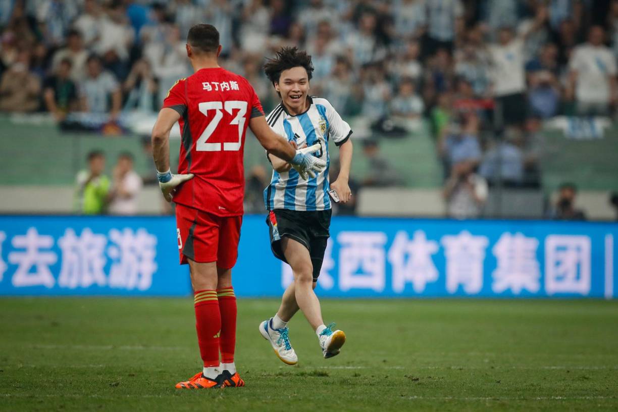 Un aficionado chino burló la seguridad e invadió el terreno de las acciones. El asiático saludó al portero Dibu Martínez.