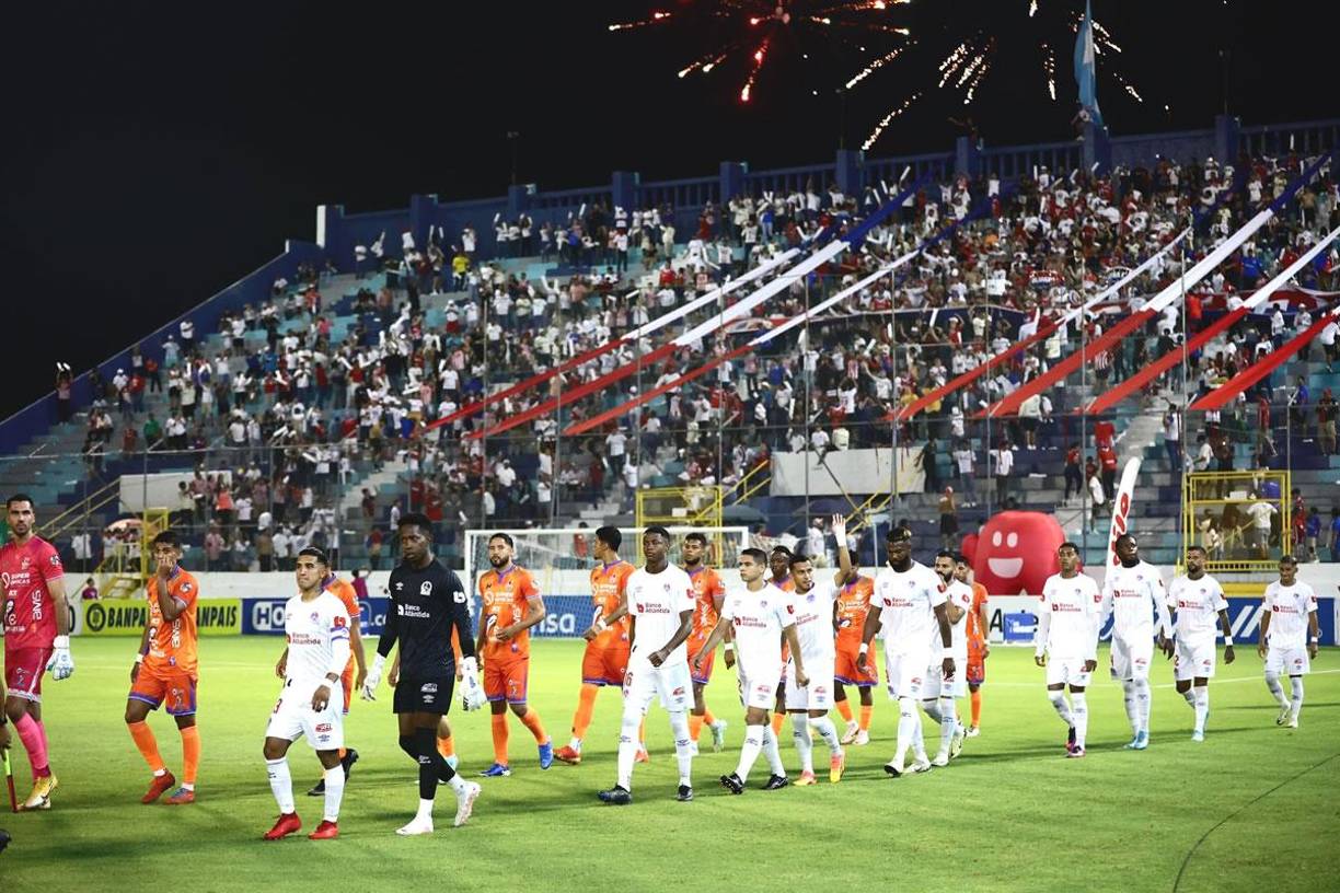 Los equipos titulares de Olimpia y UPN saliendo a la cancha del Morazán bajo fuegos artificiales.