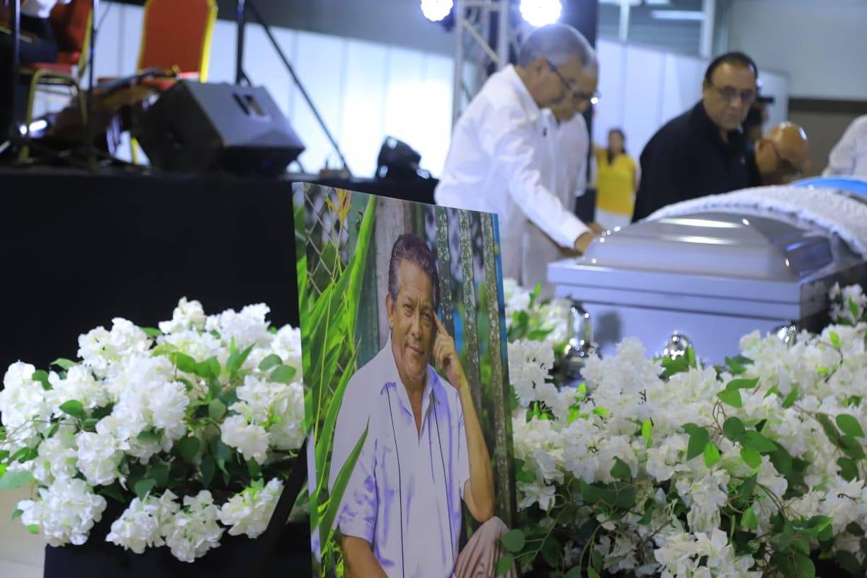 El féretro donde reposan los restos del cantautor hondureño está adornado con la bandera de Honduras, hermosos arreglos florales y una fotografía del artista. 