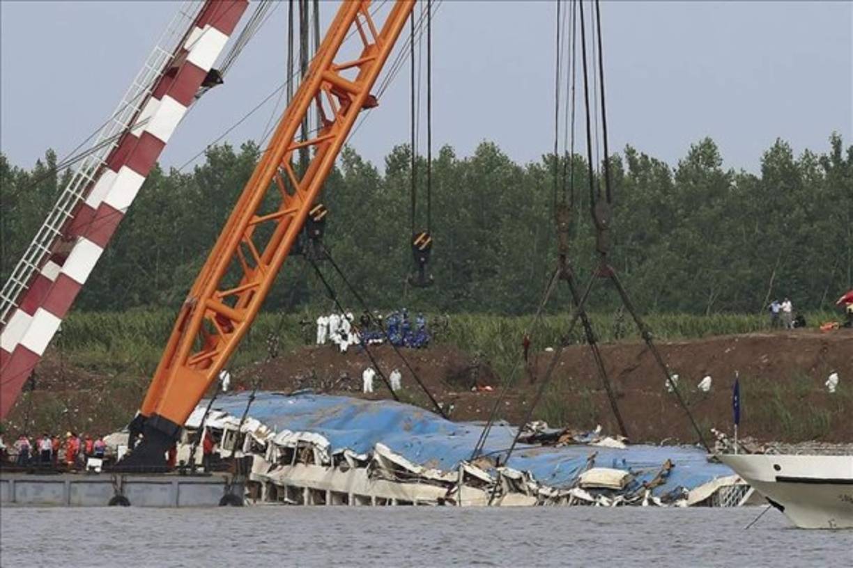 Una grúa sacó ayer del agua el barco naufragado en el río Yangtsé en Jianli, China. Los familiares de los desaparecidos en el naufragio del 'Estrella Oriental' el lunes protestaron en una de las ruedas de prensa diarias organizada por las autoridades. EFE