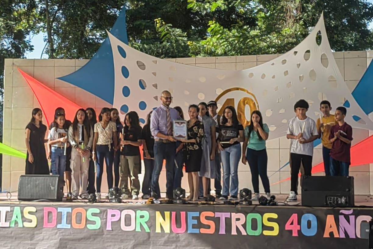 El docente de Artística, Wilson Alas, mientras recibe el reconocimiento por la subdirectora del Instituto Roberto Micheletti Baín.