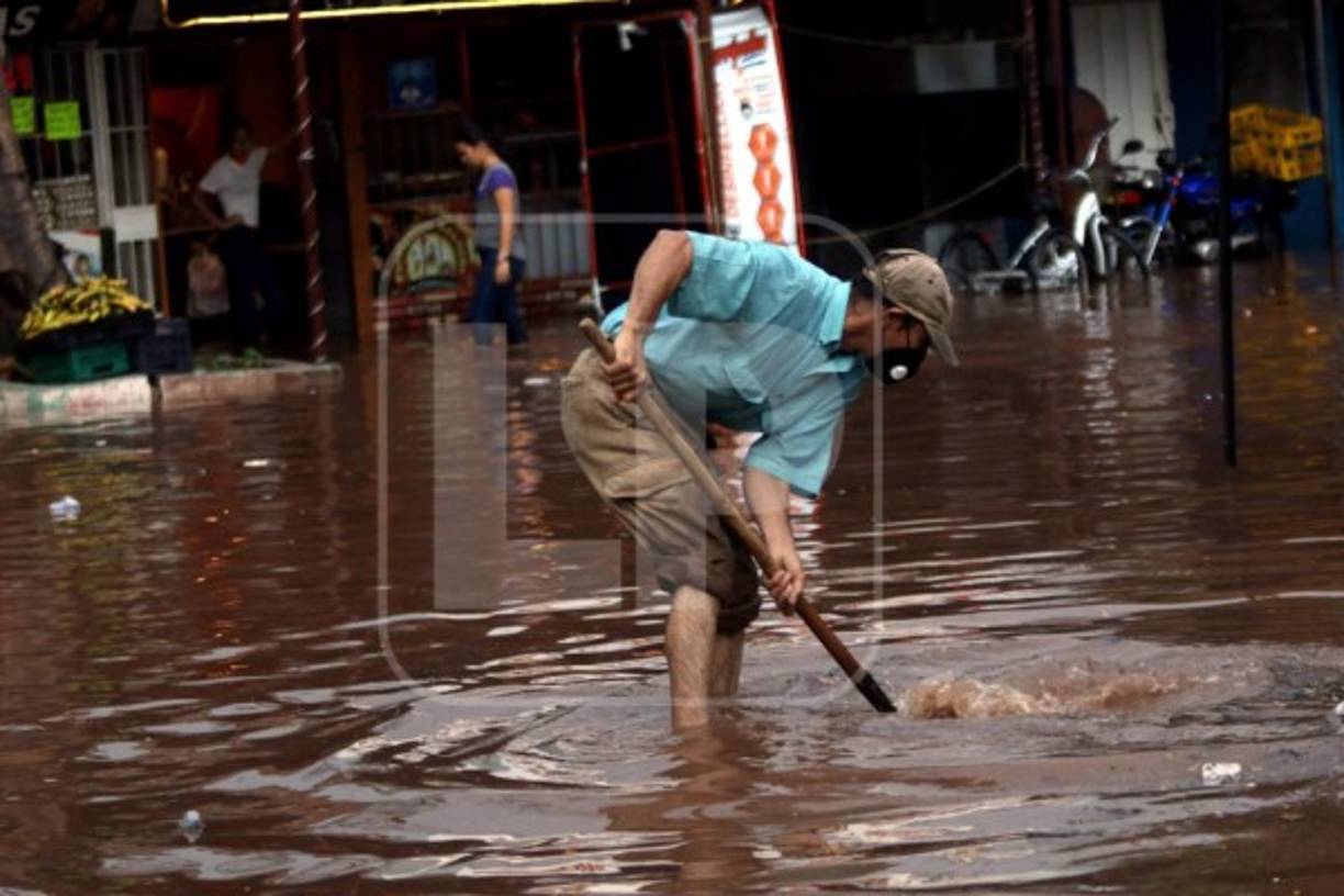 Un vecino de la colonia Kennedy intenta desbloquear un canal de agua lluvia.