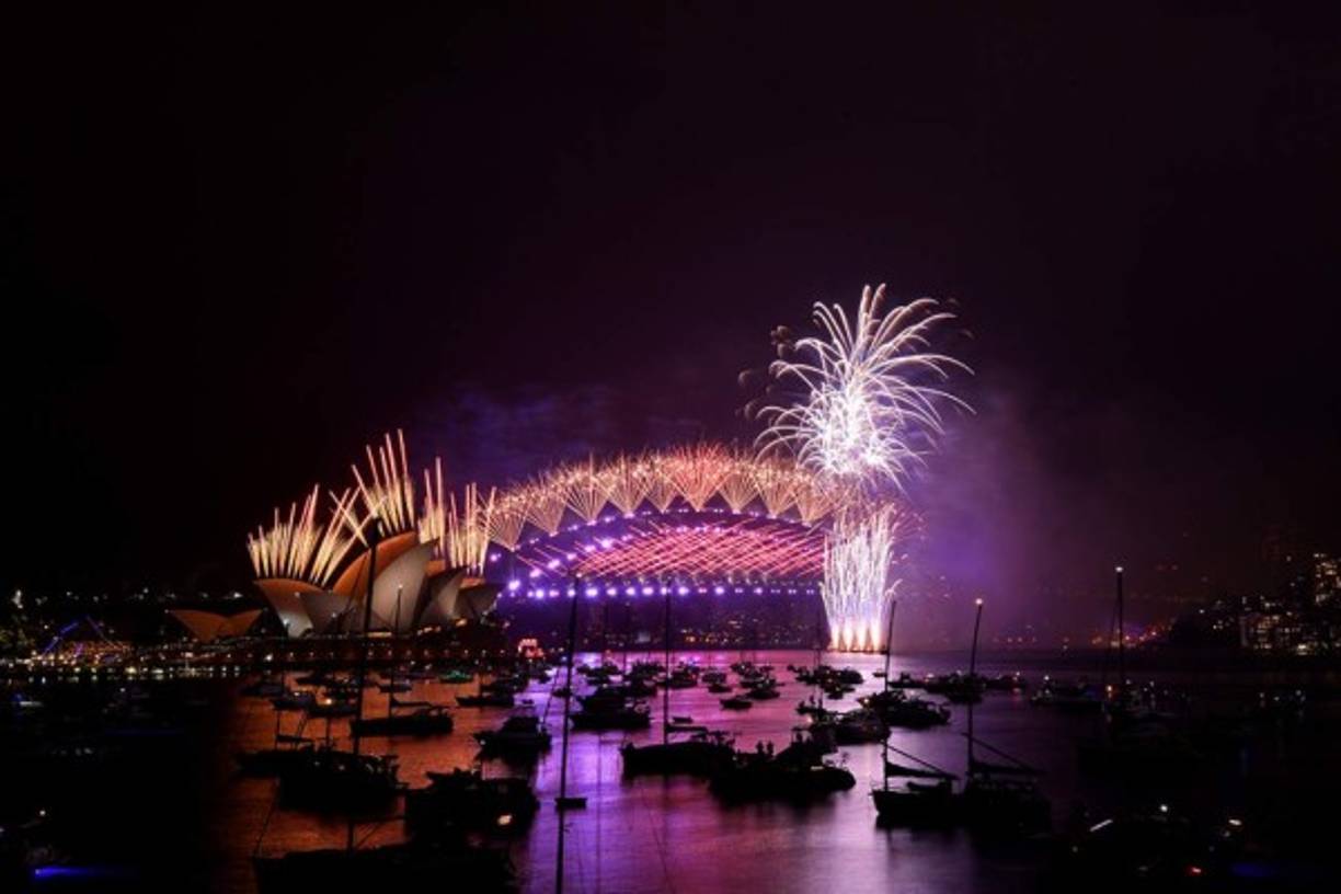 Los fuegos artificiales de Nochevieja estallan sobre el icónico Harbour Bridge y la Ópera (L) de Sydney durante el espectáculo de fuegos artificiales
