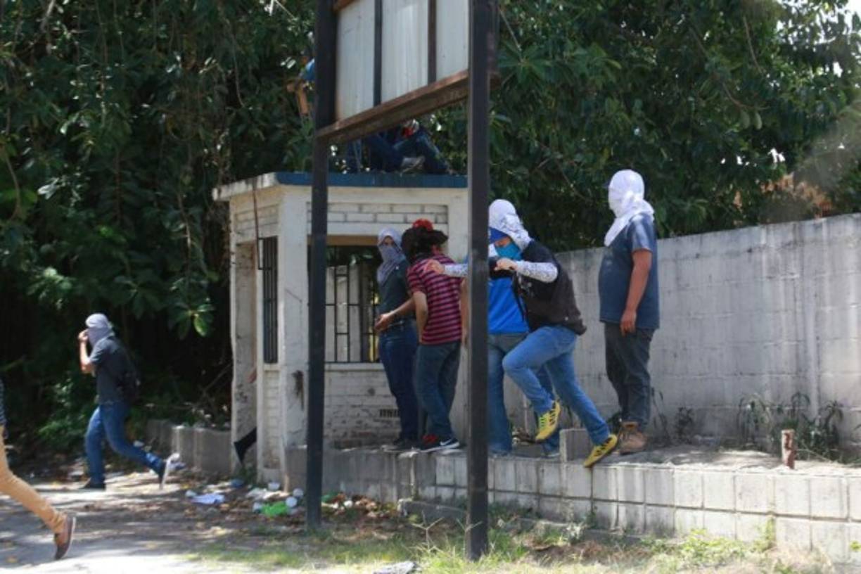 Los universitarios encapuchados vigilan la parte de atrás de la Unah-vs ante la amenaza de desalojo.