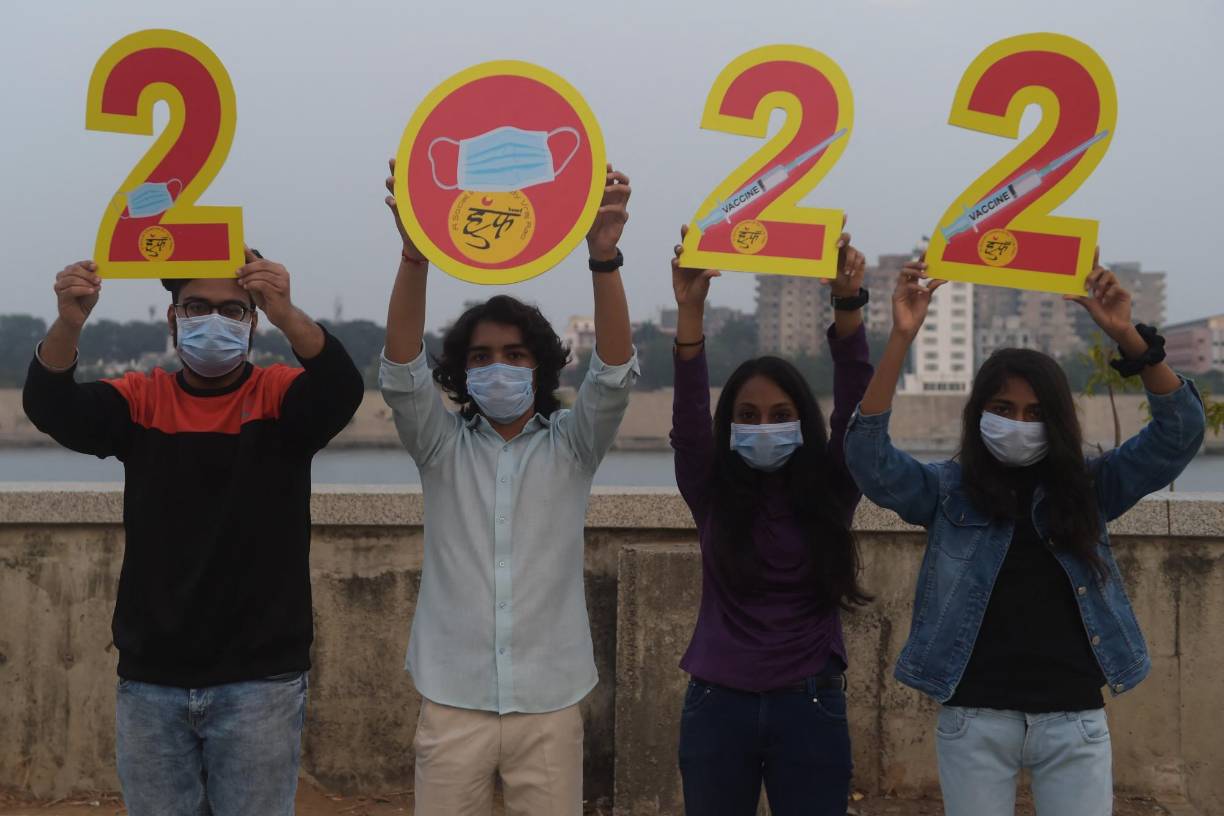 Jóvenes sostienen carteles con números para el año 2022 para instar a los jóvenes entre las edades de 15 a 18 a vacunarse contra el coronavirus Covid-19.