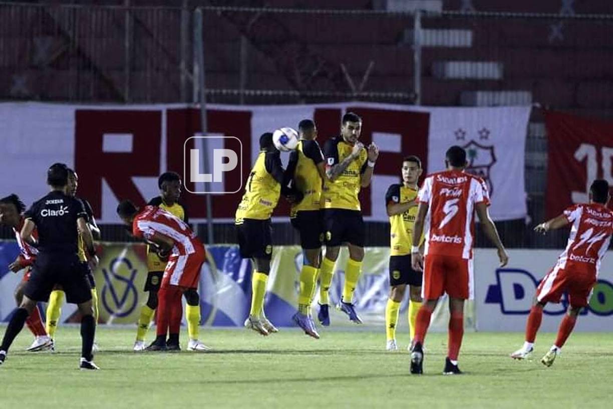 La barrera del Real España salta para bloquear un tiro libre de Alexander Aguilar.