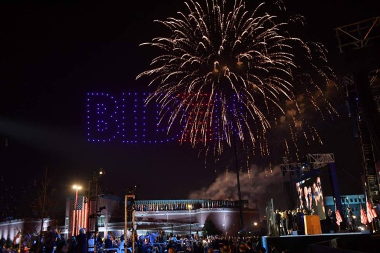 Fireworks are launched as illuminated drones spell BIDEN in the sky as US President-elect Joe Biden with his wife doctor Jill Biden alongside Vice President-elect Kamala Harris and her husband Douglas Emhoff and their families watch in Wilmington, Delaware, on November 7, 2020, after being declared the winners of the presidential election. - Democrat Joe Biden was declared winner of the US presidency November 7, defeating Donald Trump and ending an era that convulsed American politics, shocked the world and left the United States more divided than at any time in decades. (Photo by ANGELA WEISS / AFP)