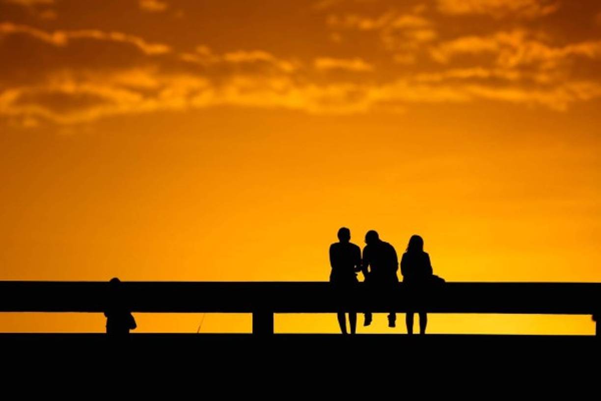 BRASIL. Atarceder en negro y amarillo. Tres brasileños observan el ocaso en la capital Brasilia, un momento de paz en medio de la tensión política.