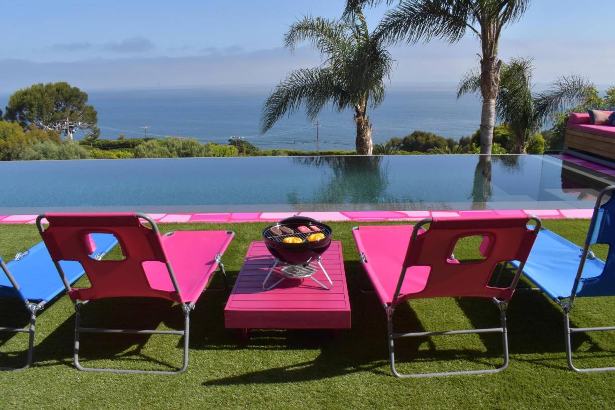 El césped sintético y un par de camastros de color rosa y azul visten el área exterior que cuenta con una piscina infinita, esta sí de verdad, mientras un pasillo de celosías vibrantes conducen al cuarto de Barbie y Ken, el lugar más importante de la casa. 