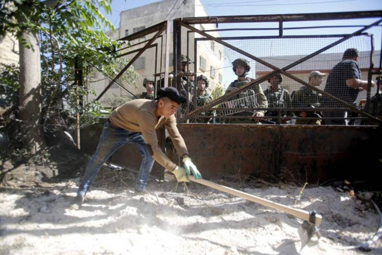 SOLIDARIDAD. Operación limpieza en Tal Rumaida. Soldados del ejército israelí vigilan a los activistas palestinos, israelíes y estadounidenses que realizan labores de limpeza en casas palestinas. Foto: EFE/Abed Al Hashlamoun
