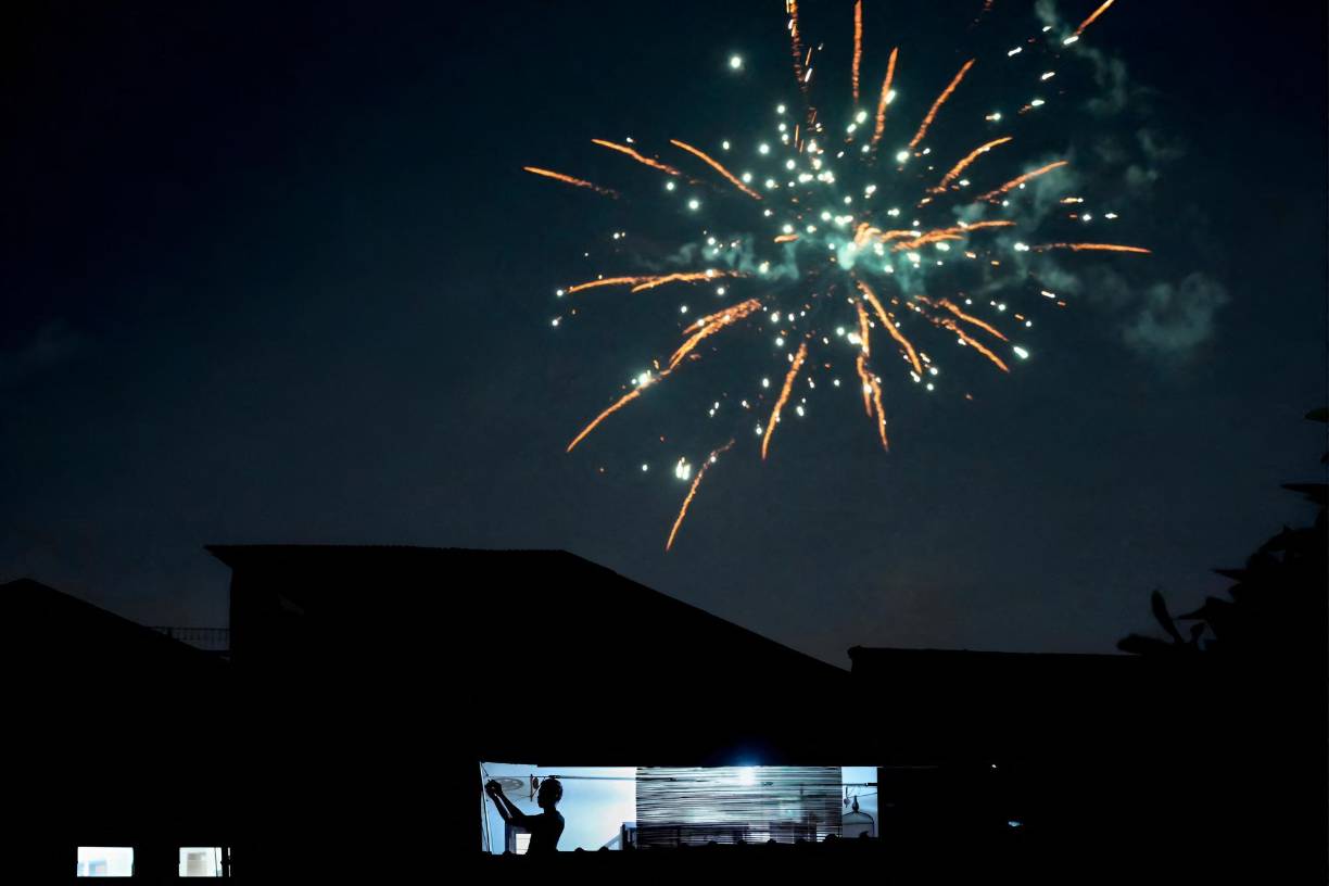 <b>Indonesia</b>Un transeúnte toma fotografías de los fuegos artificiales en exhibición para celebrar el Año Nuevo en Yakarta, el 1 de enero de 2023. 