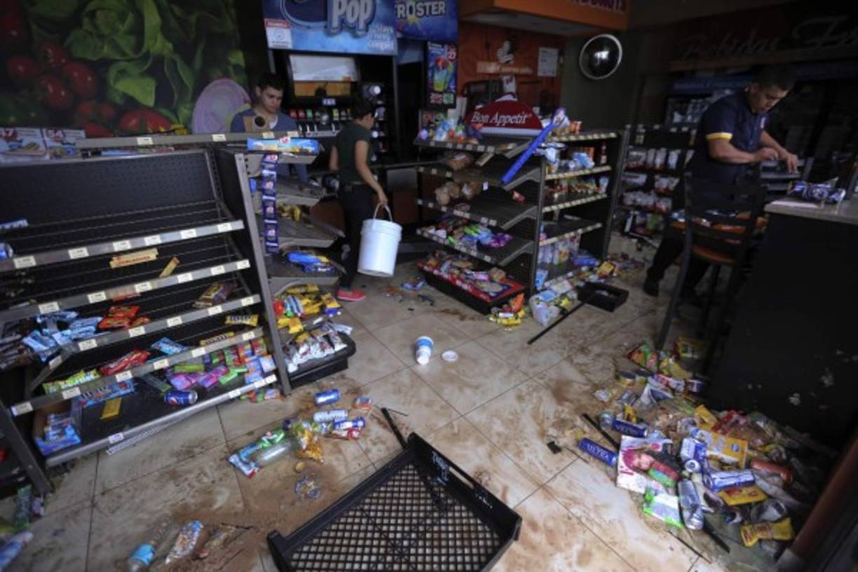 Empleados de un negocio limpian el local que fue saqueado por maniestantes en la madrugada del pasado viernes.