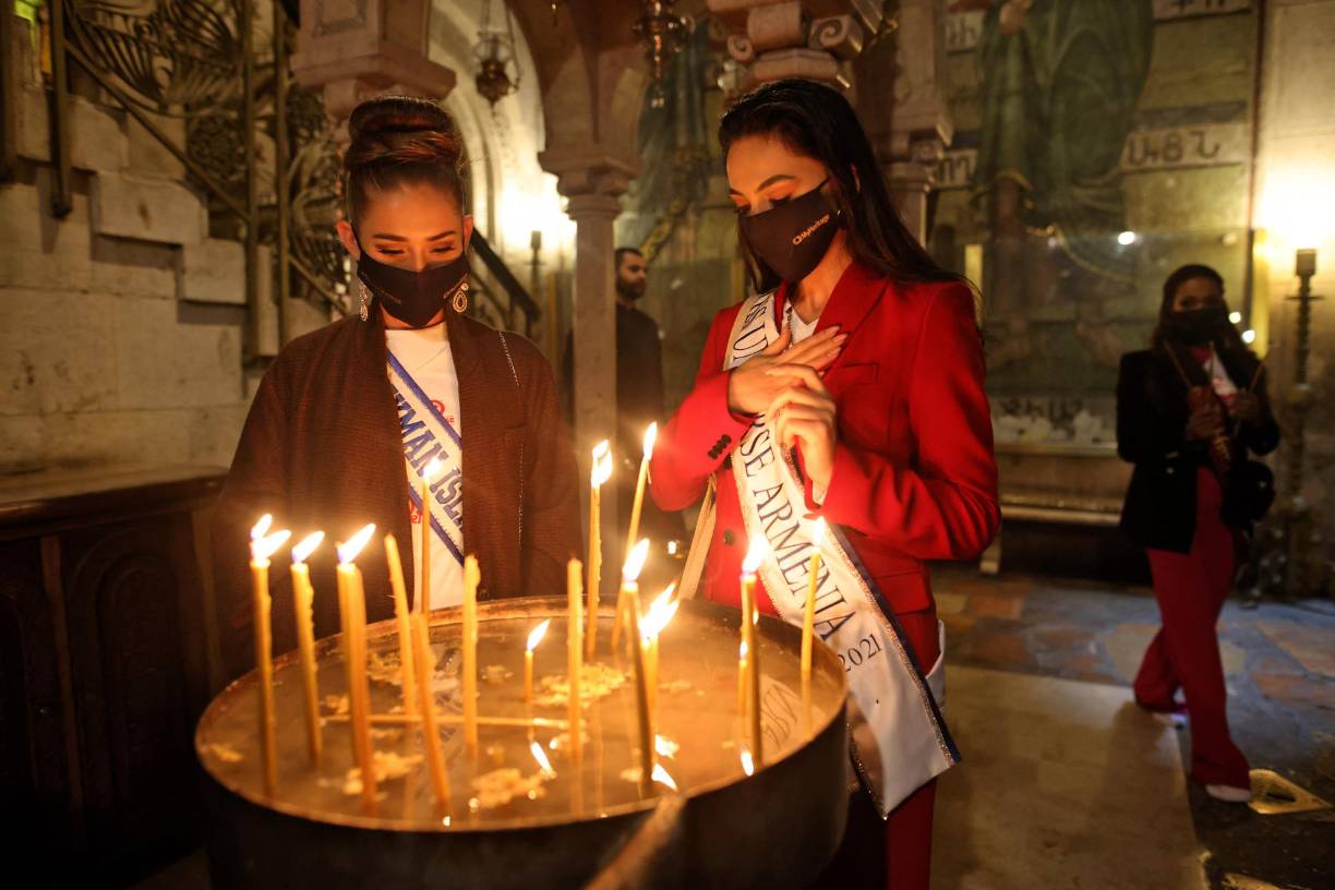 Miss Islas Caimán y Miss Armenia encienden velas en el Santo Sepulcro en la Ciudad Vieja de Jerusalén.