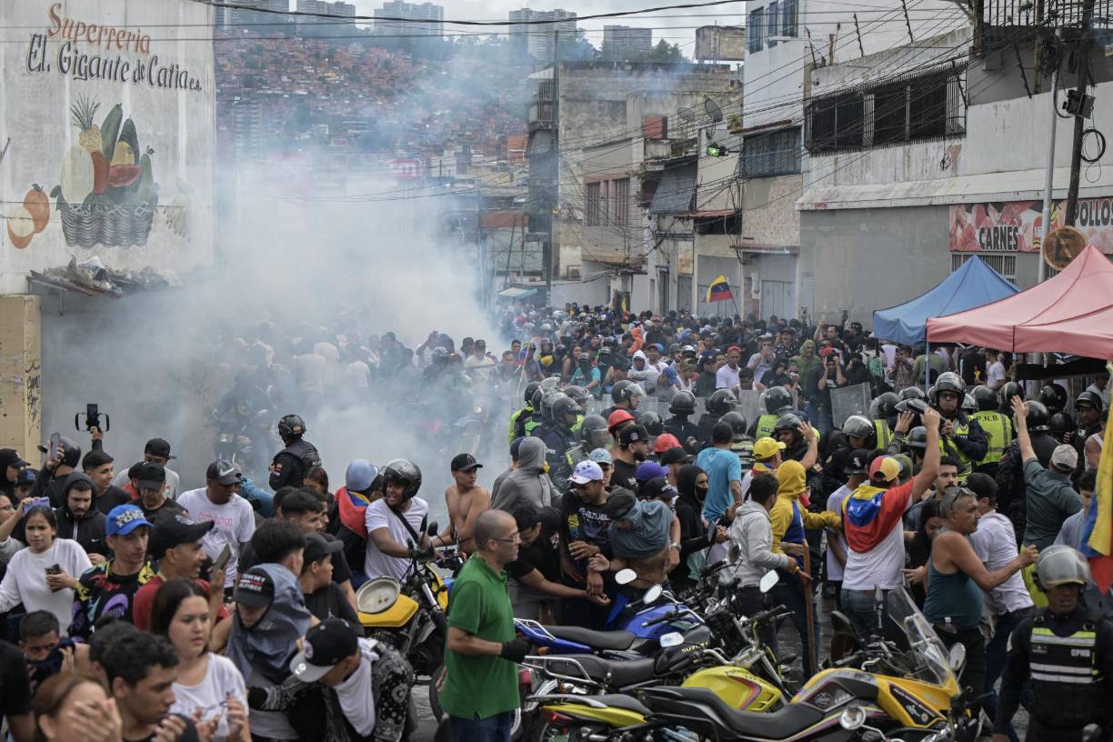 Opponents of Venezuelan President Nicolas Maduro's government confront riot police during a protest in the Catia neighborhood of Caracas on July 29, 2024, a day after the Venezuelan presidential election. Protests erupted in parts of Caracas Monday against the re-election victory claimed by Venezuelan President Nicolas Maduro but disputed by the opposition and questioned internationally, AFP journalists observed. (Photo by Yuri CORTEZ / AFP)