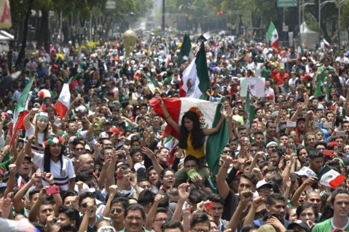 Una aficionada mexicana es cargada en los hombros mientras sostiene la bandera de México.