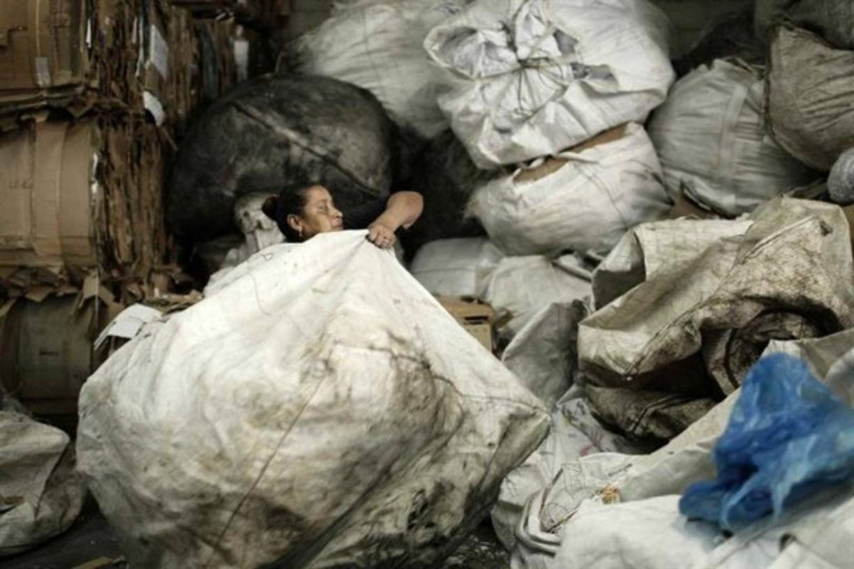 Una mujer reciclando en San José (Costa Rica). Mucho del material recolectado por los 'cartoneros' es ordenado y separado para su reciclaje. Invisibles ante los ojos de los transeúntes citadinos, los 'cartoneros', en su mayoría indigentes, al ritmo de las hormigas de trabajo recolectan los cartones desperdigados de los comercios de la capital en San José, Costa Rica. La suma del material recopilado por los cartoneros puede ascender a 8 toneladas diarias, según comenta Víctor Calvo, propietario del centro de reciclaje donde se realiza el acopio de los desechos en San José. Con una paga por kilo de 35 colones ($0,06), se convierte en un pequeño ingreso para estas personas que en su mayoría son dependientes de las drogas y que por esta labor muchos han dejado de robar. EFE/Jeffrey Arguedas<br/>