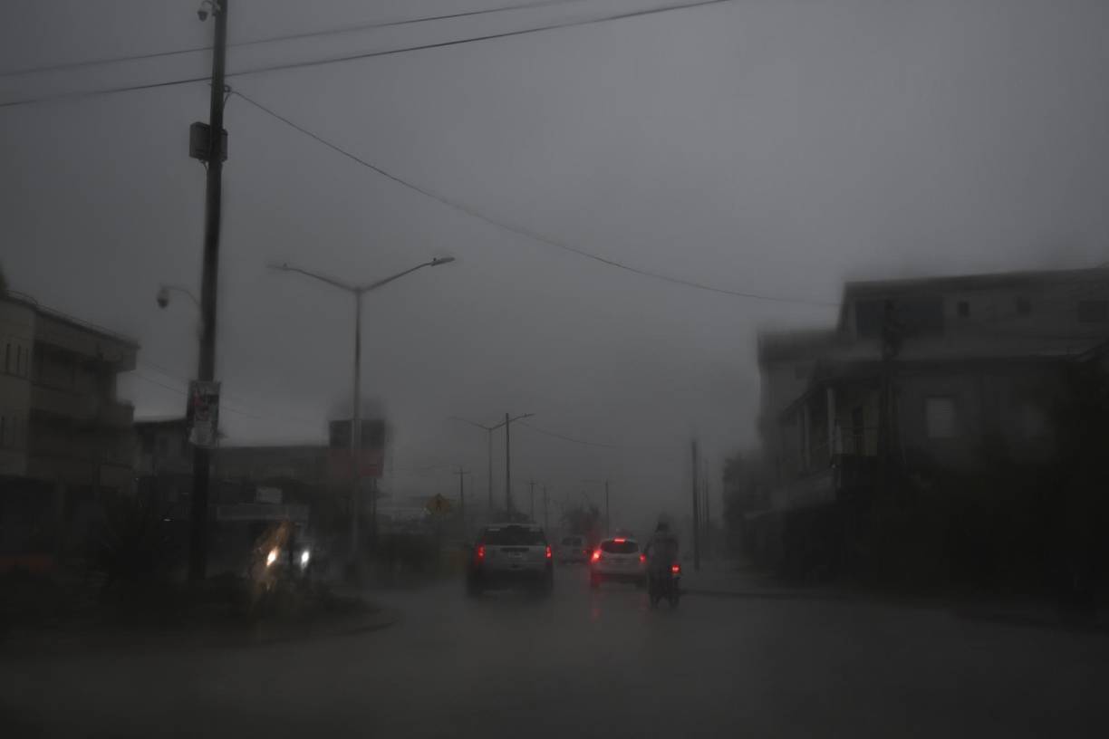 Vehicles make their way through a street flooded due to heavy rains before the arrival of Hurricane Lisa in Belize City on November 2,2022. - The northern part of Central America was on high alert Wednesday for the passage of Hurricane Lisa, with warnings of devastating winds, downpours and flash floods also affecting Mexico's Yucatan peninsula. (Photo by Johan ORDONEZ / AFP)