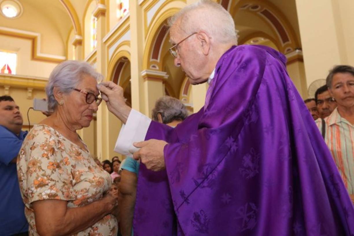 El sacerdote Raúl Najarro impone la cruz de ceniza en la frente a una feligrés.