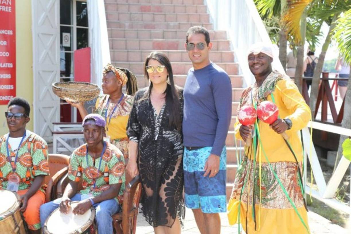 Una pareja de turistas se toman fotos con un grupo de danza garífuna.