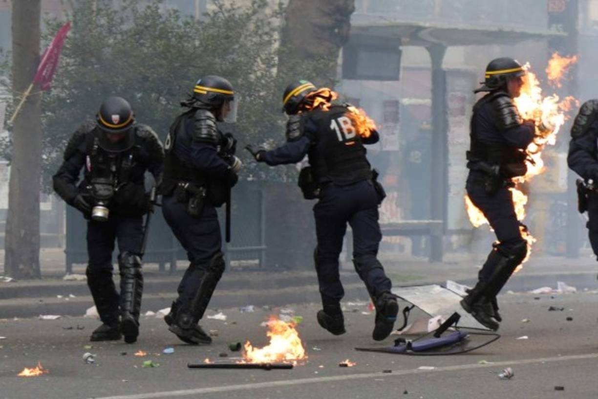 French CRS anti-riot police officers are engulfed in flames as they face protesters during a march for the annual May Day workers' rally in Paris on May 1, 2017. / AFP PHOTO / Zakaria ABDELKAFI