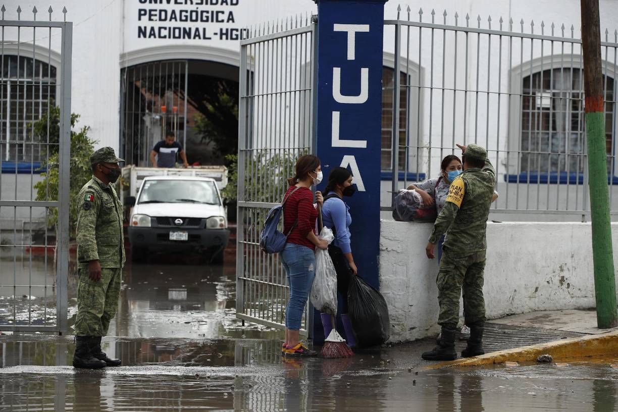 Armados con palas, los habitantes del centro de la ciudad trabajan para destapar las alcantarillas en busca de que se vaya el agua que todavía queda en las calles.