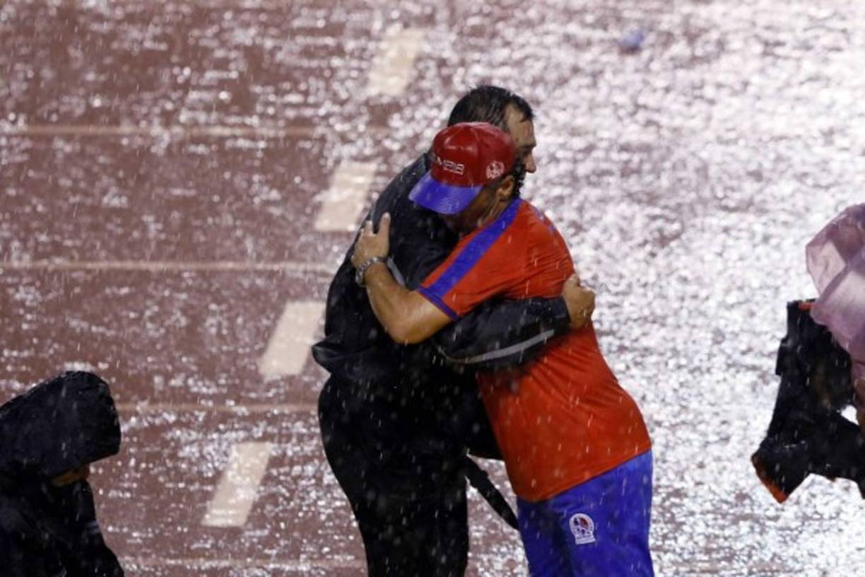 El abrazo entre Pedro Troglio y el entrenador del Comunicaciones, Mauricio Tapia, bajo la lluvia que cayó sobre San Pedro Sula.