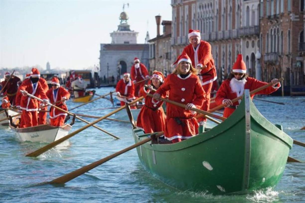 Decenas de personas vestidos de Santa Claus navegan en góndolas en Venecia.