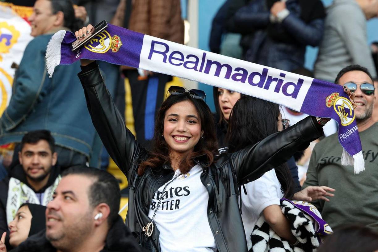 Esta hermosa aficionada del Real Madrid sonríe miestras sostiene una bufanda del equipo blanco.