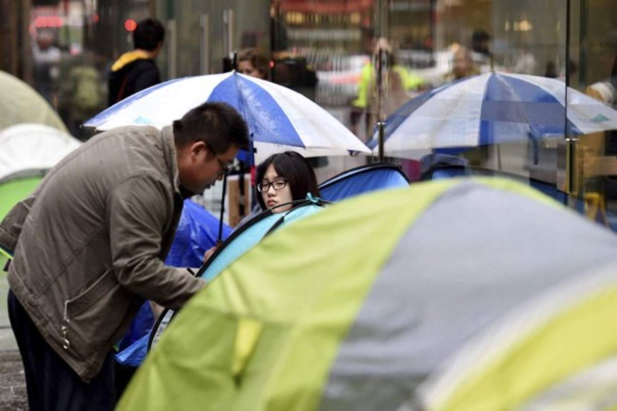 No importa la lluvia, los consumidores, armados con sombrillas, hacen todo lo que sea por ser los primeros en comprar el nuevo iPhone.