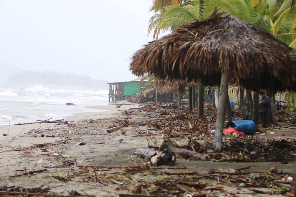 La arena blanca bañada por el mar ha sido cubierta por plásticos, barriles, restos de palmas y troncos que han sido arrastrados por el mar.