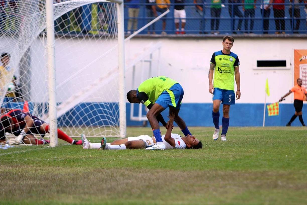 José Mario Pinto, tendido en el suelo siendo ayudado por Óscar Almendárez para pararse.