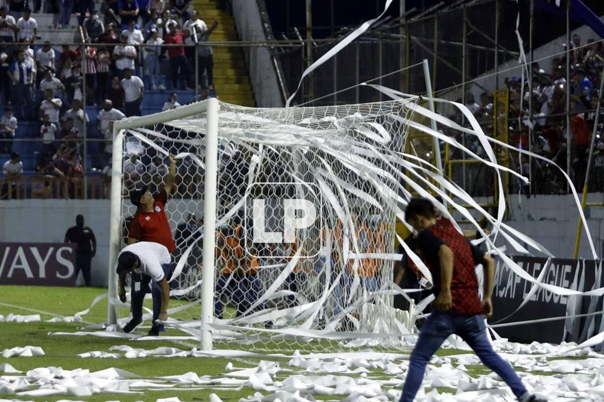 Miembros del staff del Olimpia tuvieron que sacar los papeles del campo antes del inicio del partido.