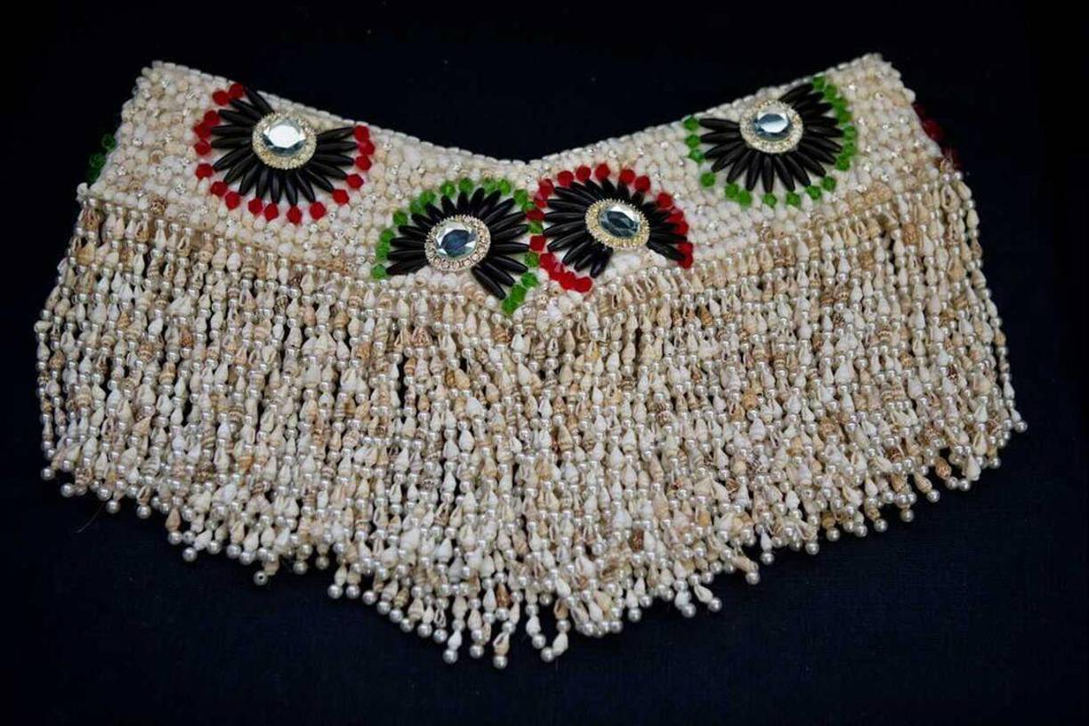 La falda y la blusa están adornadas con caracoles y perlas que muestran la belleza de la mujer.