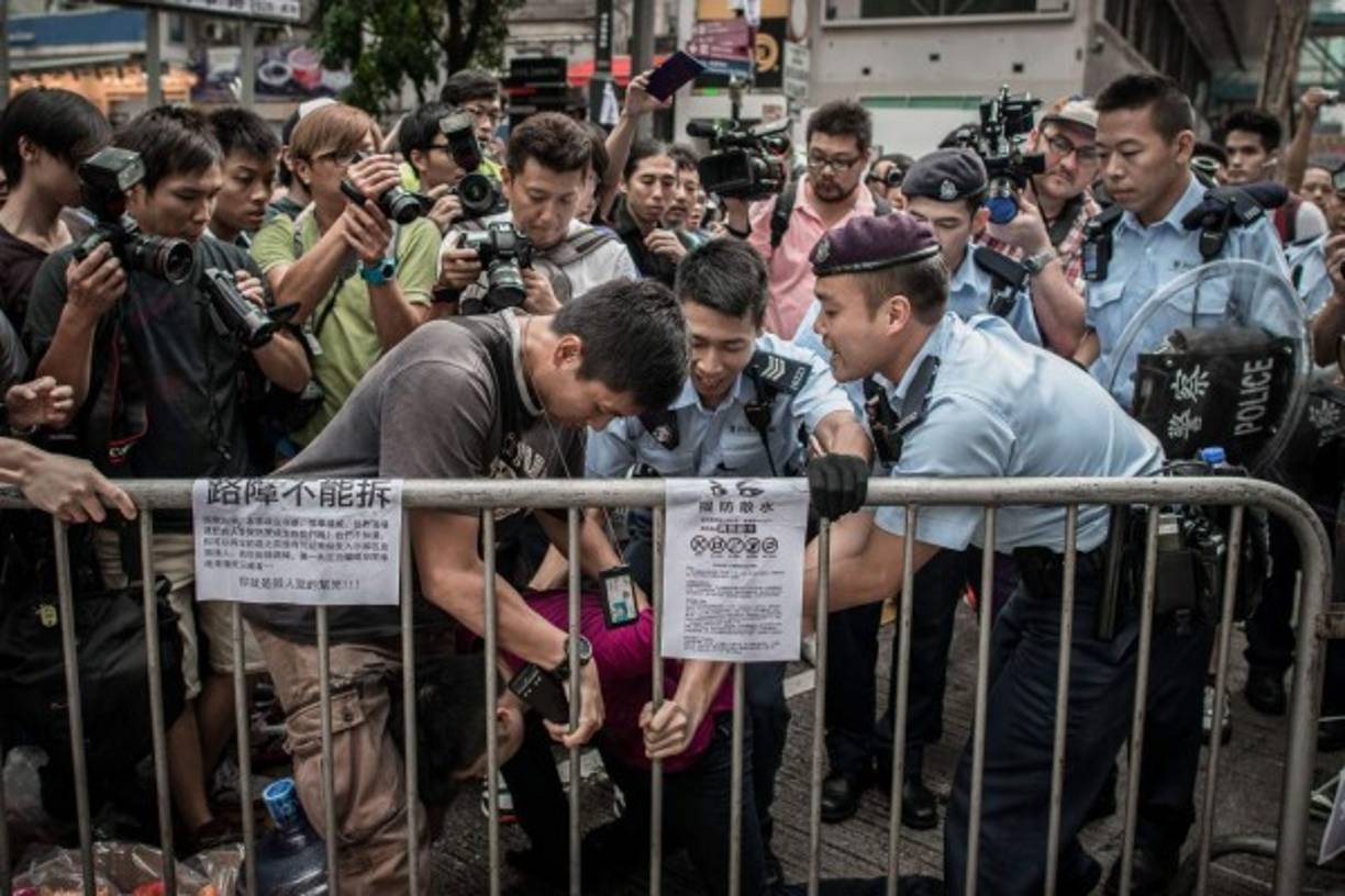 Policías tratan de controlar a un hombre para que deje la valla custodiada por los manifestantes pro-democracia en una zona ocupada de Hong Kong el 3 de octubre de 2014. AFP