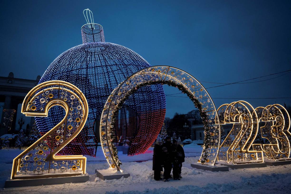 A family poses for a picture in front of Christmas and New Year decorations in Moscow on December 19, 2022. (Photo by Natalia KOLESNIKOVA / AFP)