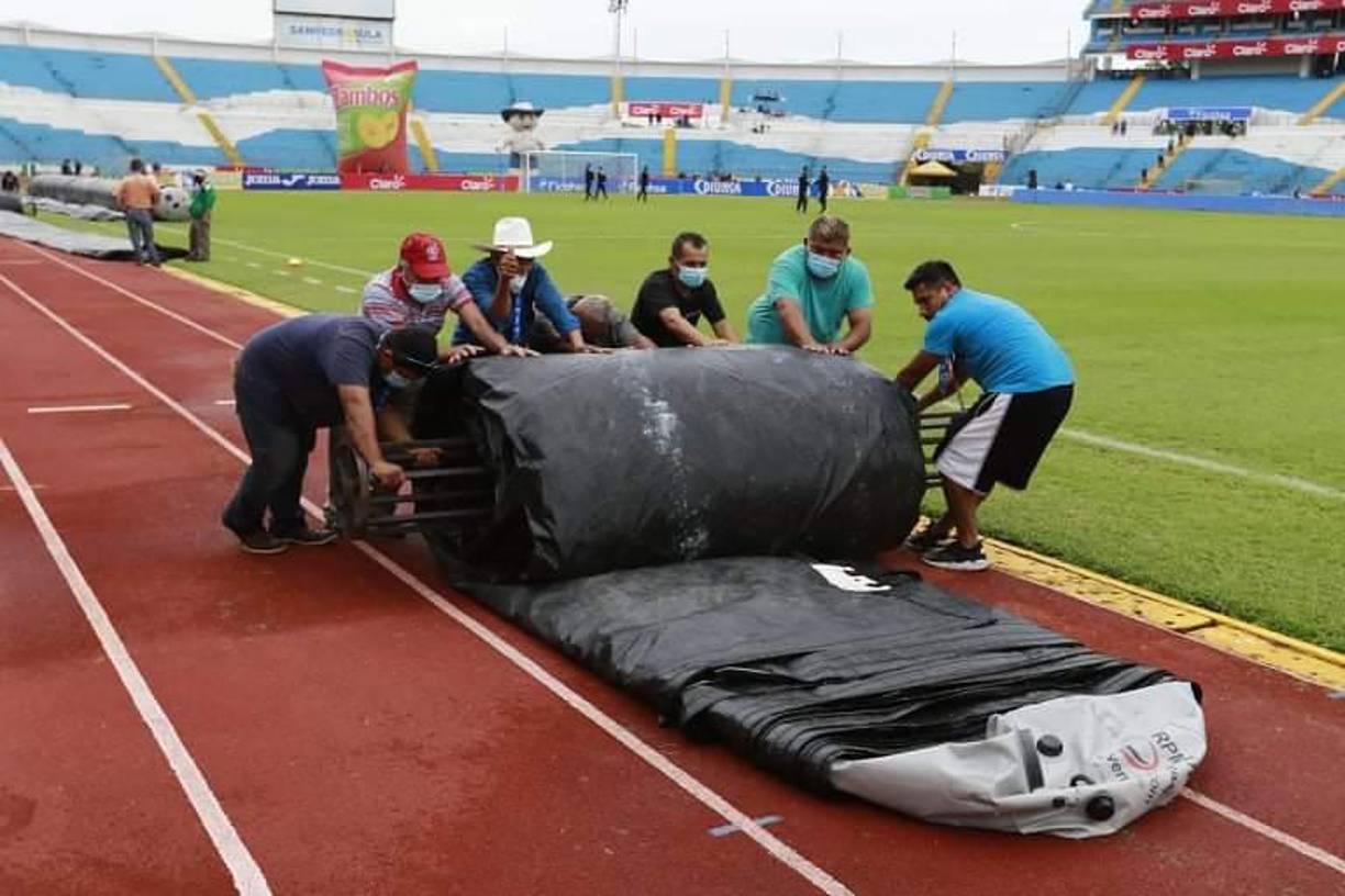 Personal del estadio Olímpico mientras guardaban la lona que cubrió la cancha por la lluvia que ha caído sobre San Pedro Sula.