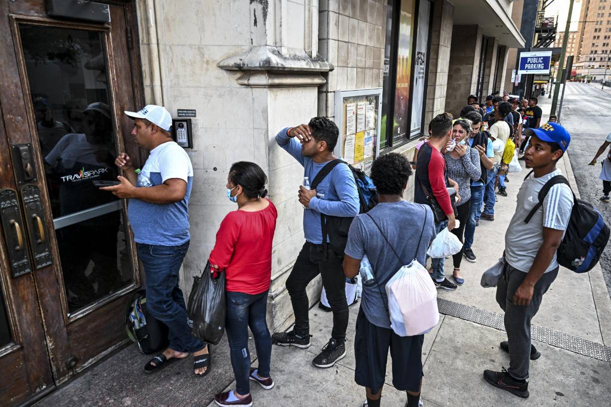 Migrants wait outside a shelter in San Antonio, Texas on June 29, 2022. - Dozens of migrants wait in line outside a shelter in San Antonio, most of them young men but also some women and children, hoping for a hot meal and a roof over their head. Every year thousands like them pass through this Texas city that is on the front line of the struggle to cope with waves of migrants seeking to escape poverty and violence and find a better life in the US. And the trip can be deadly: 53 people died this week after being left inside a big-rig truck abandoned by some train tracks and junk yards in San Antonio. (Photo by CHANDAN KHANNA / AFP)