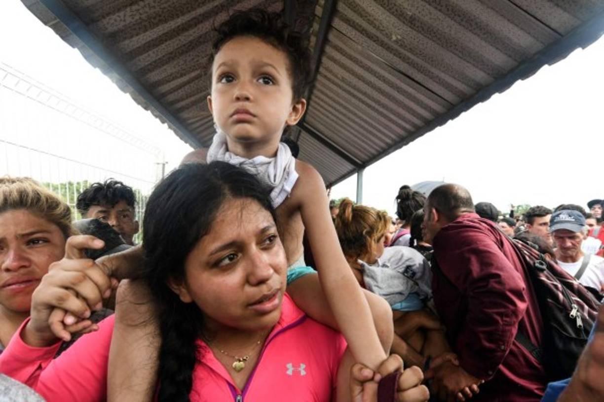 La incertidumbre del viaje se refleja en el rostro de esta mujer que viaja con su pequeño en hombros.