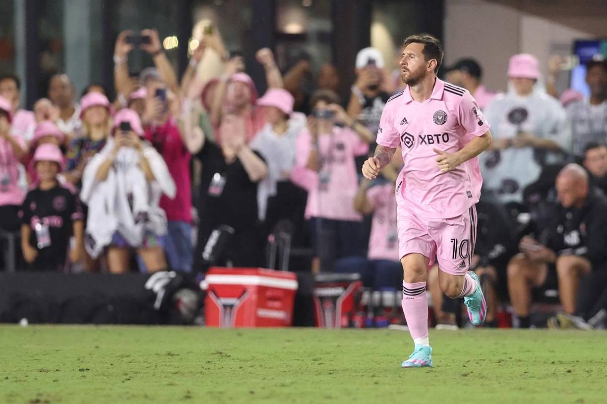 El delantero argentino campeón del mundo entrando a la cancha y al fondo se ve a los aficionados celebrando su regreso.