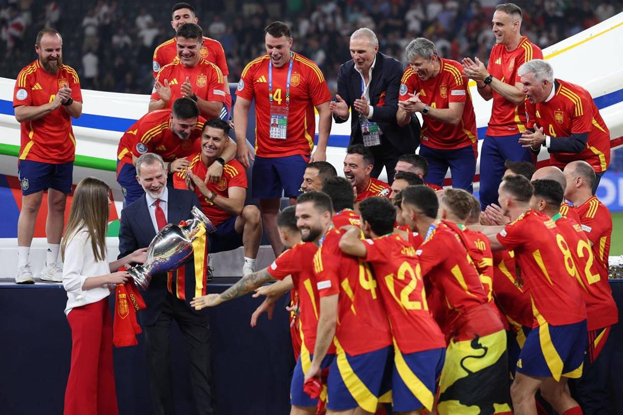 El rey Felipe VI de España, flanqueado por la princesa Sofía, sostiene el trofeo y celebra con los jugadores después de ganar la final de la Euro 2024.