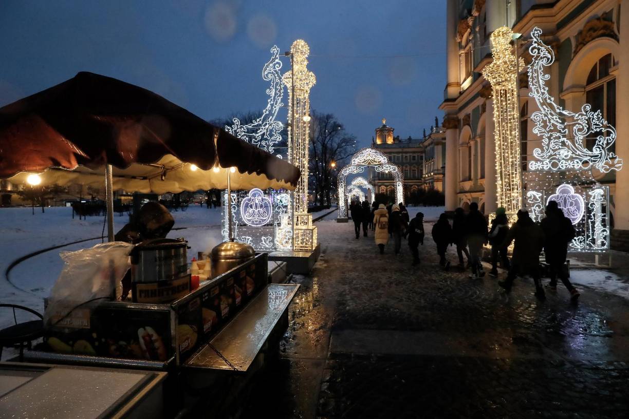 La gente camina frente al Museo Estatal del Hermitage, decorado estacionalmente antes de las celebraciones de año Nuevo y Navidad, en San Petersburgo.