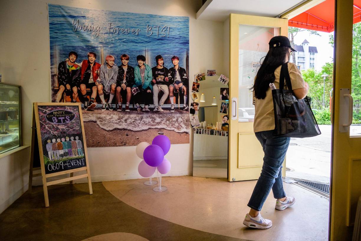 Un cliente pasa frente a un póster de las megaestrellas del K-pop BTS dentro de un café en Seúl.